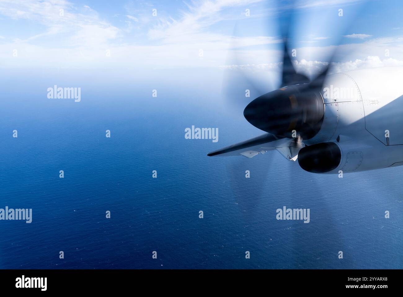 Wingview Propeller Plane Flying Over the Atlantic Ocean With Vibrant Blue Sky and Clouds Stock Photo