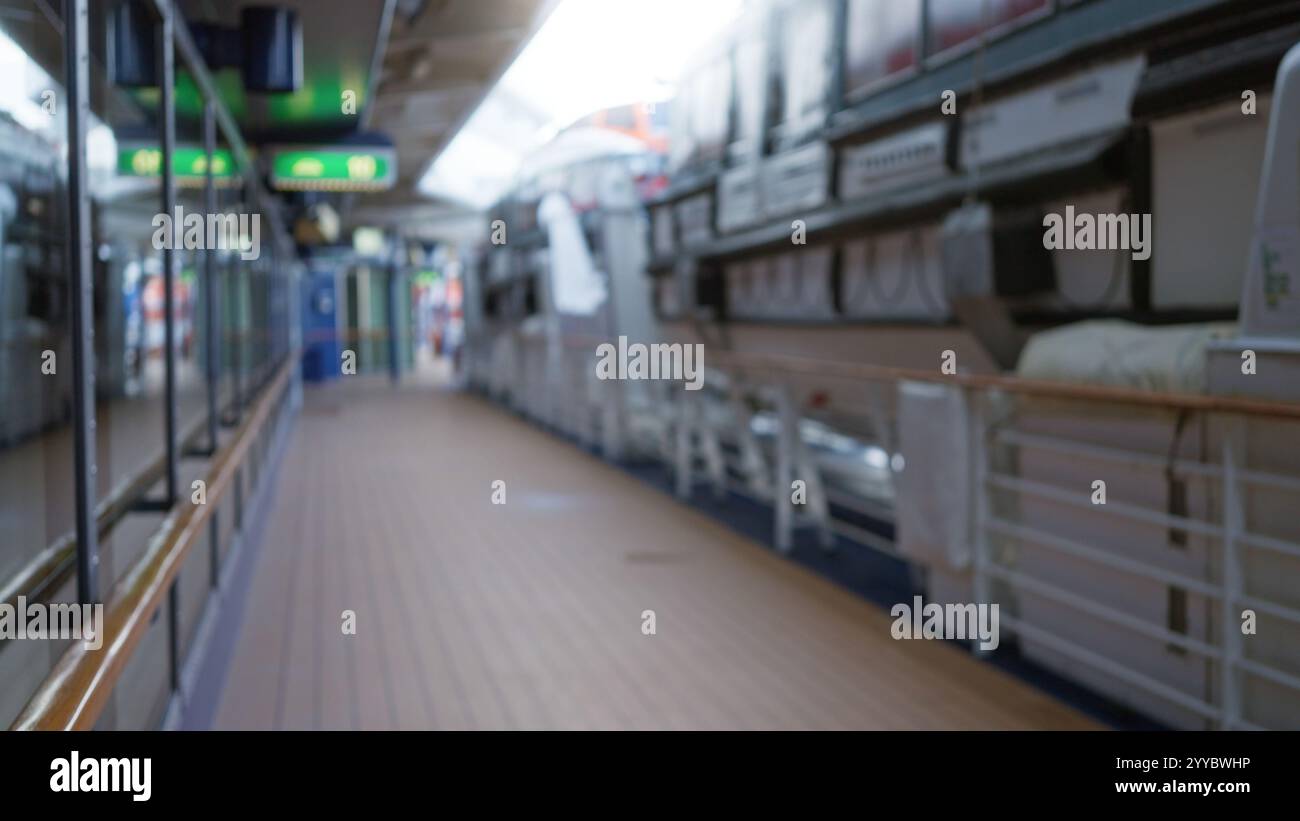 Blurred view of a cruise ship deck outdoors with lifeboats, showcasing defocused bokeh effect and a calm atmosphere under clear skies. Stock Photo
