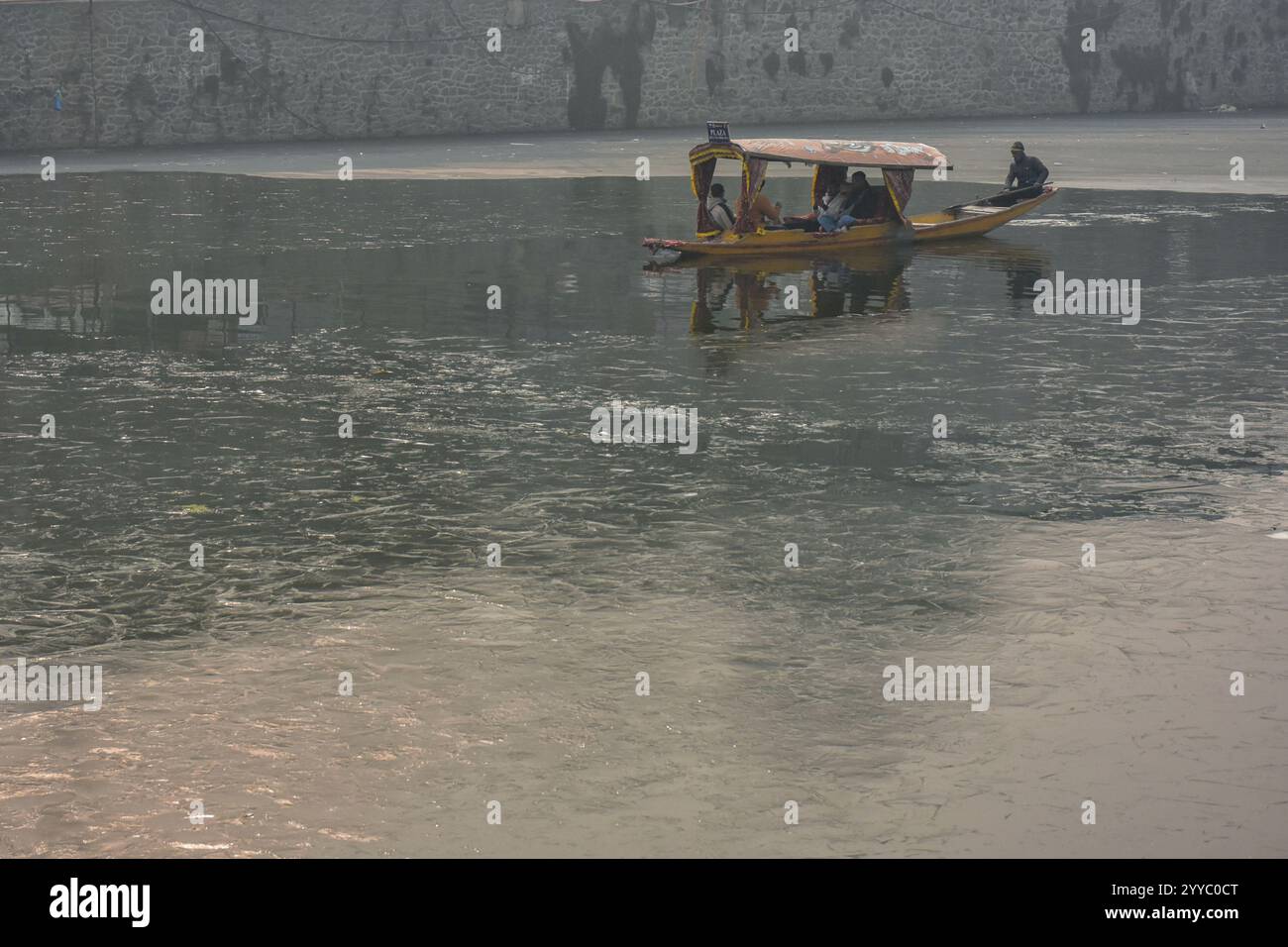 a-boatman-ferries-tourists-across-the-partially-frozen-dal-lake