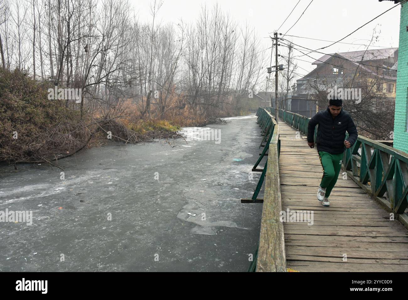 a-man-runs-along-the-wooden-foot-bridge-as-a-dal-lake-is-seen-partially