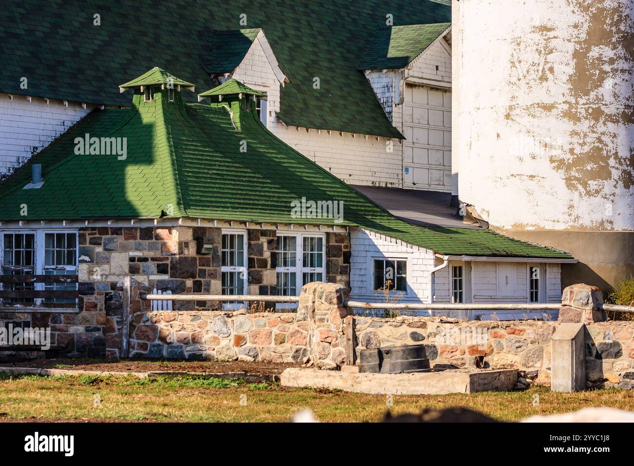 A white house with a green roof and a barn in the background. The house ...