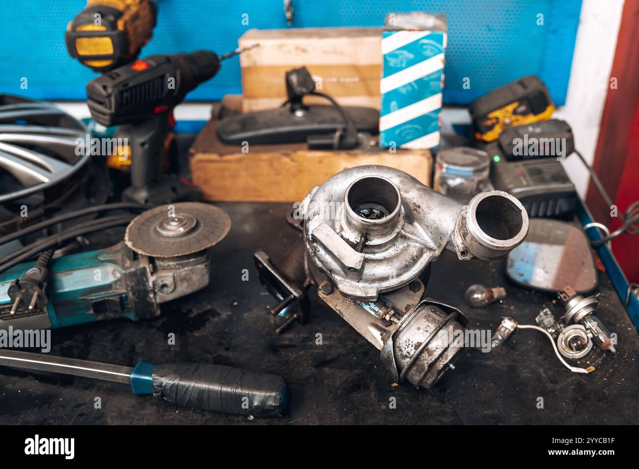 Turbocharger placed on workbench amidst tools and parts, showcasing automotive repair process Stock Photo