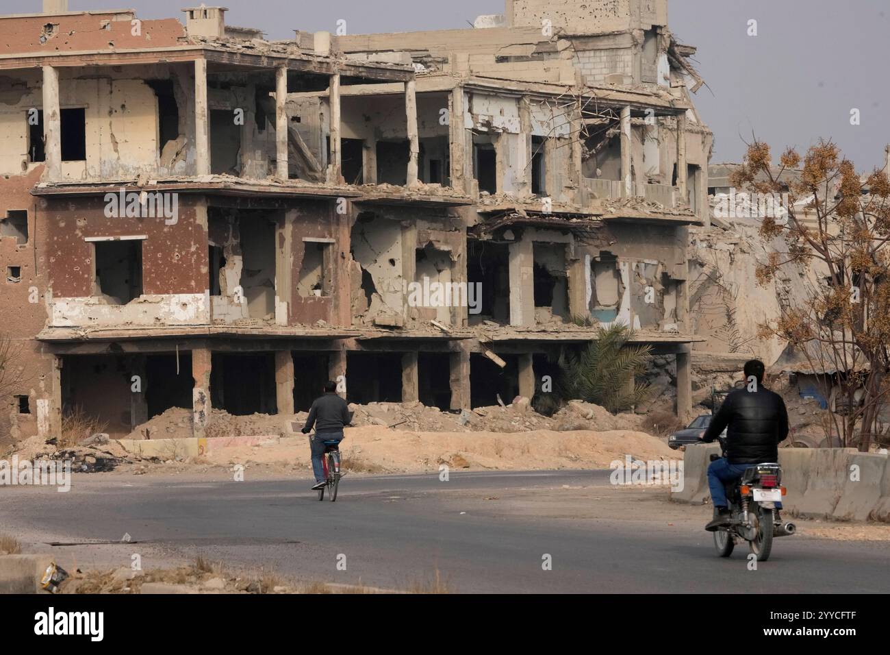 Syrians ride in front of buildings that were destroyed during the civil ...