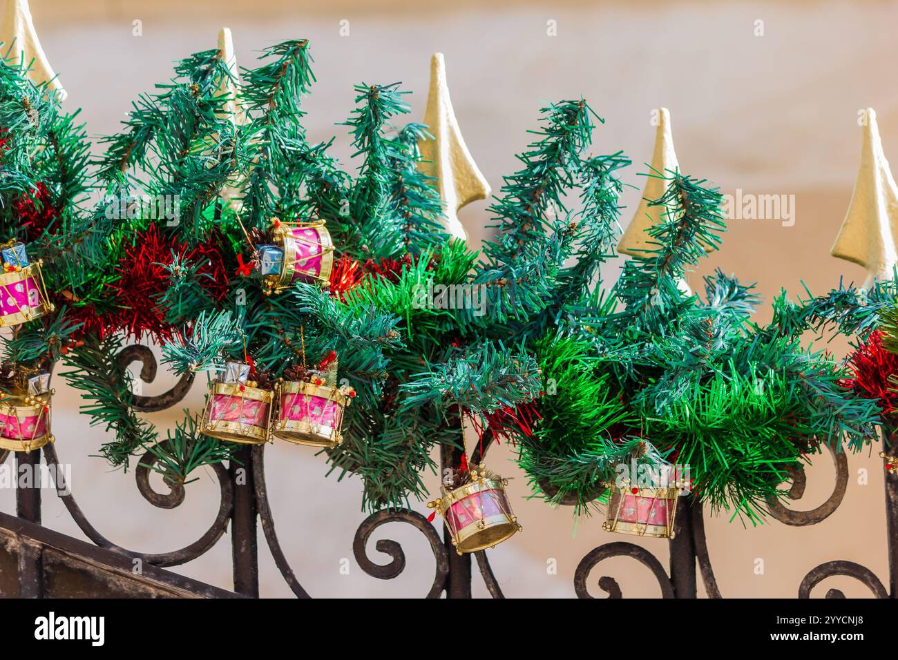 Brightly decorated Christmas garland and ornaments adorn an elegant wrought iron fence, evoking festive holiday cheer and seasonal warmth. Stock Photo