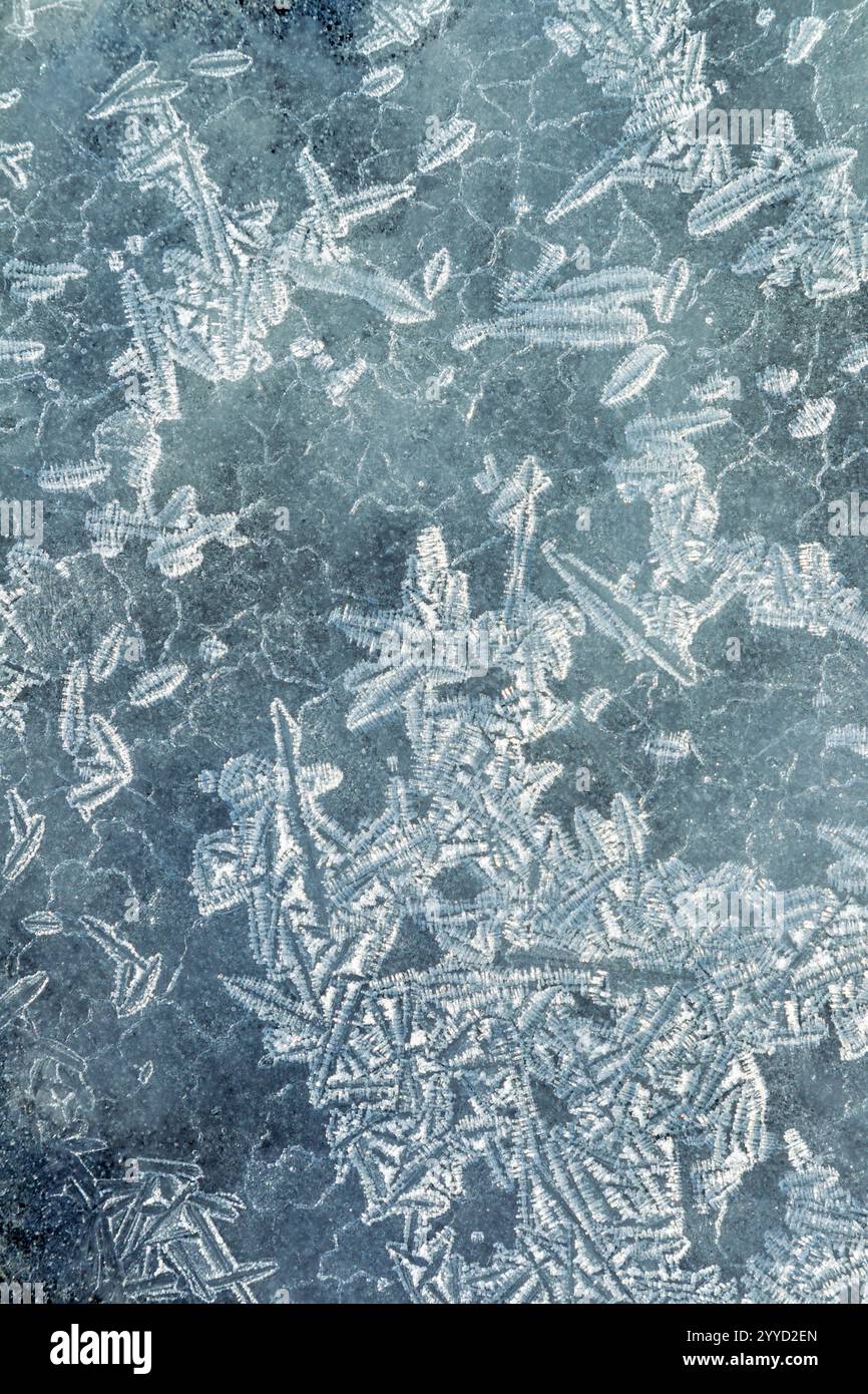 Abstract shapes and patterns formed by a variety of ice crystals on a layer of ice - Stock Image