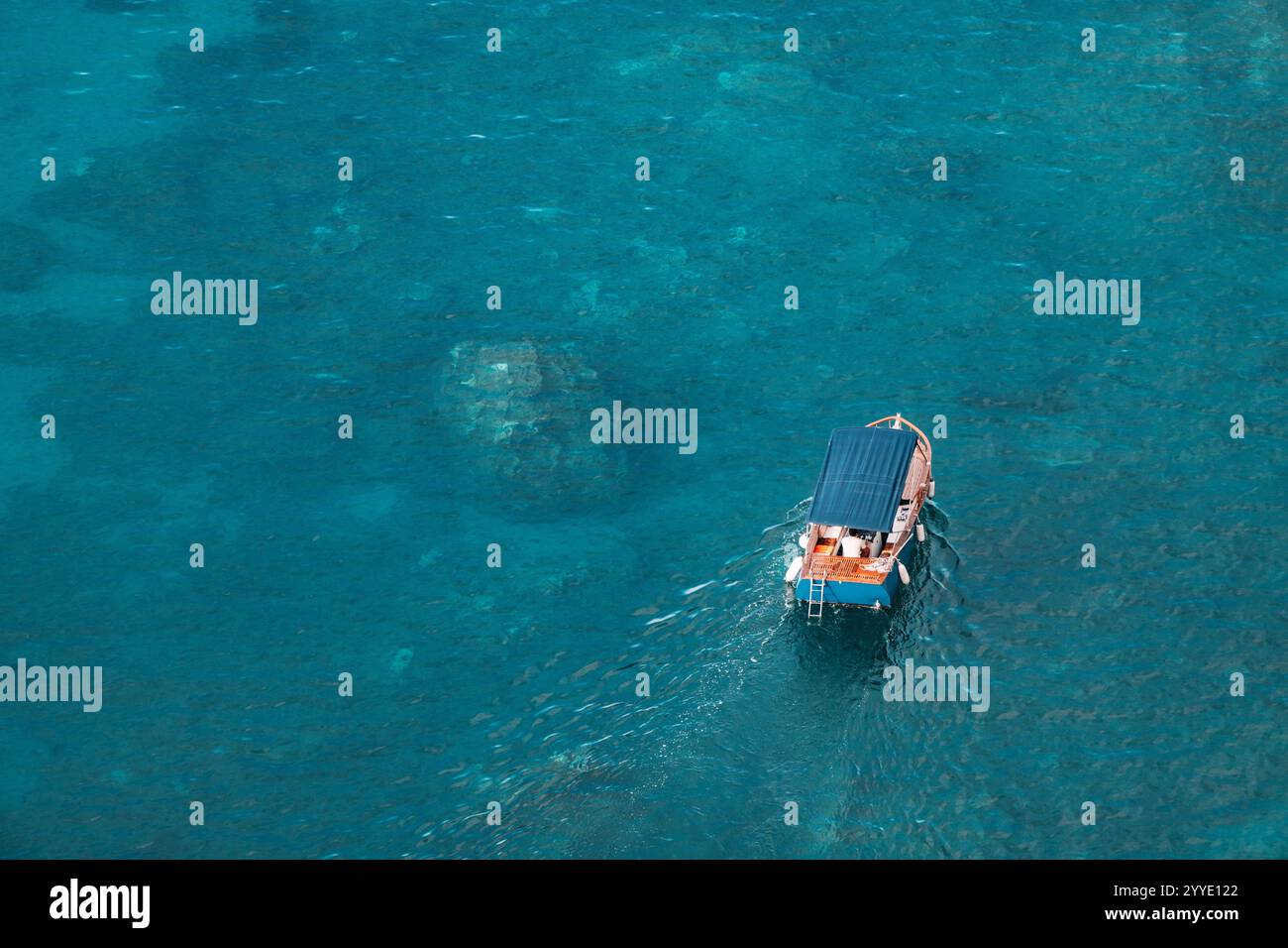 Aerial view of a small tourist boat sailing on a calm turquoise water ...