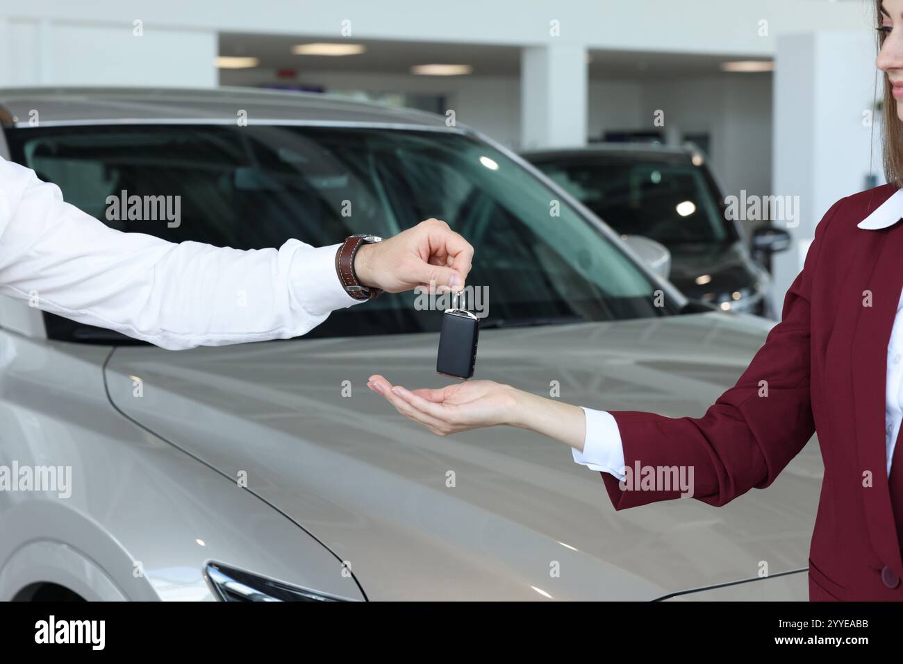 Salesman giving key to client near new car in salon, closeup Stock ...