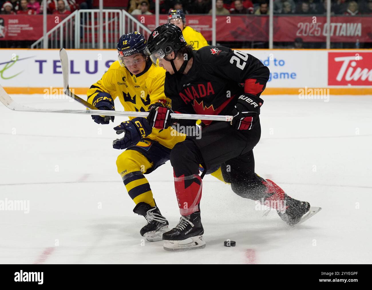 Canada forward Ethan Gauthier, right, shields the puck from Sweden