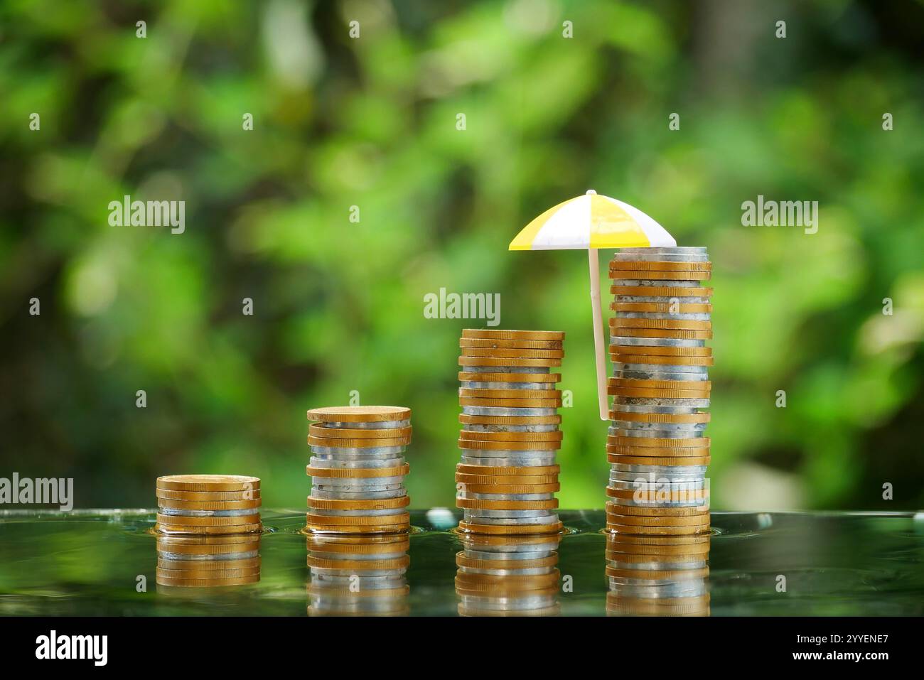Small red umbrella on a pile of coins on the table. The concept of financial security and investment, protection. Stock Photo