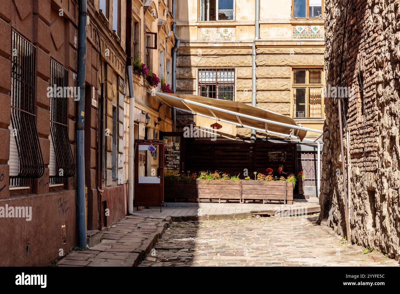 A narrow alleyway with a wooden bench and a canopy. The bench is empty and the canopy is open Stock Photo