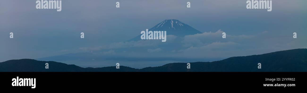 Panorama image of Mount Fuji in Japan taken during an overcast day with moodly clouds floating near the peak. Stock Photo