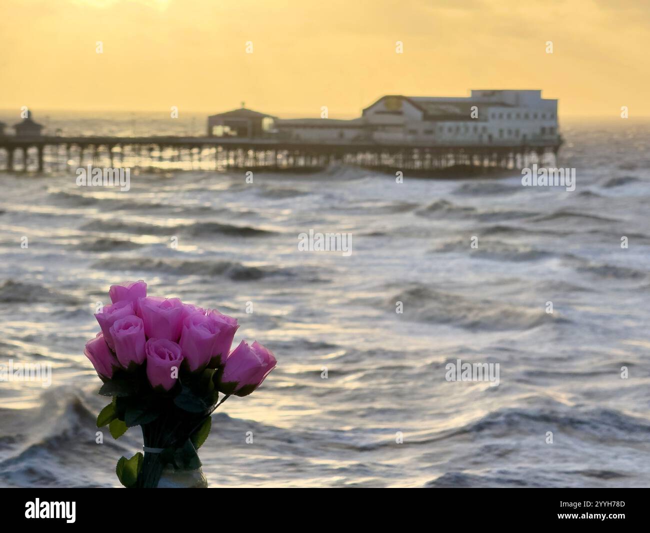 Blackpool North Pier at high tide on a windy winter evening with floral tribute in foreground - Smartphone Captured Stock Image