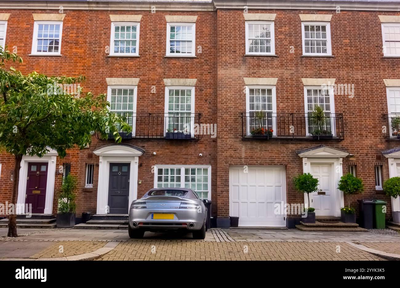 London, UK - 15 July 2023: front of expensive edwardian brick townhouse on Park Walk in Chelsea, London with Aston Martin car parked in driveway Stock Photo