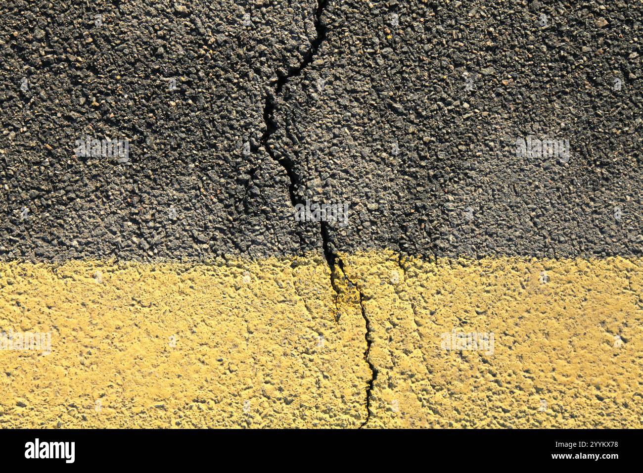 Asphalt surface and backdrop. Asphalt with a crack in middle. Road background with a yellow dividing stripe at the bottom. Detailed texture of bitumen Stock Photo