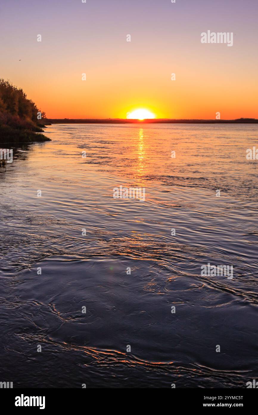 The sun is setting over a body of water, creating a beautiful and ...