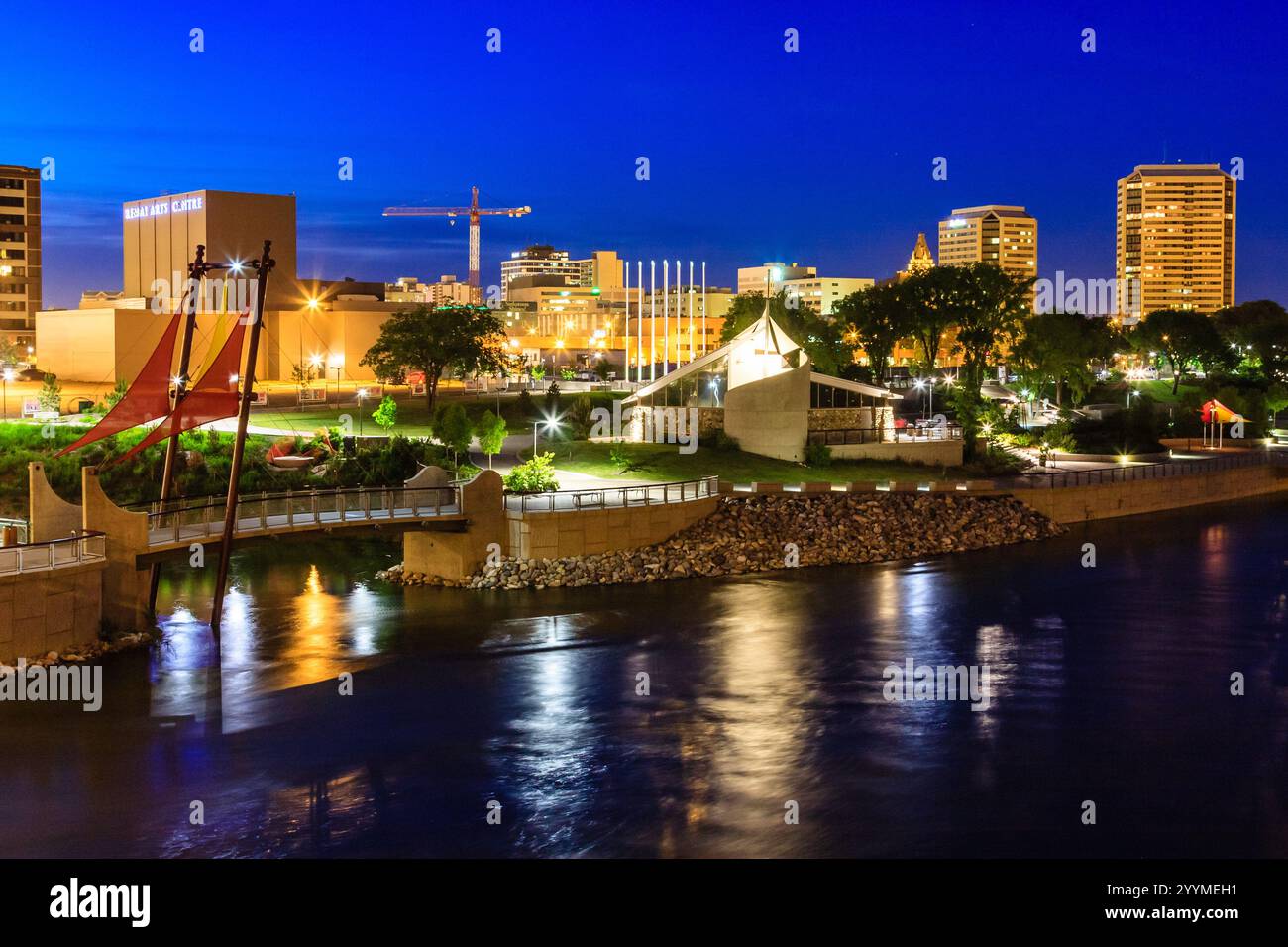 A city at night with a river running through it. The city is lit up with lights and the water is reflecting the lights Stock Photo