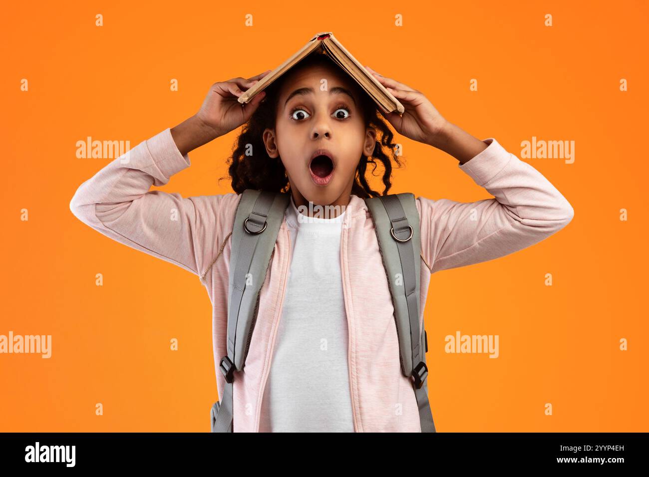Funny black girl holding open book on her head Stock Photo - Alamy