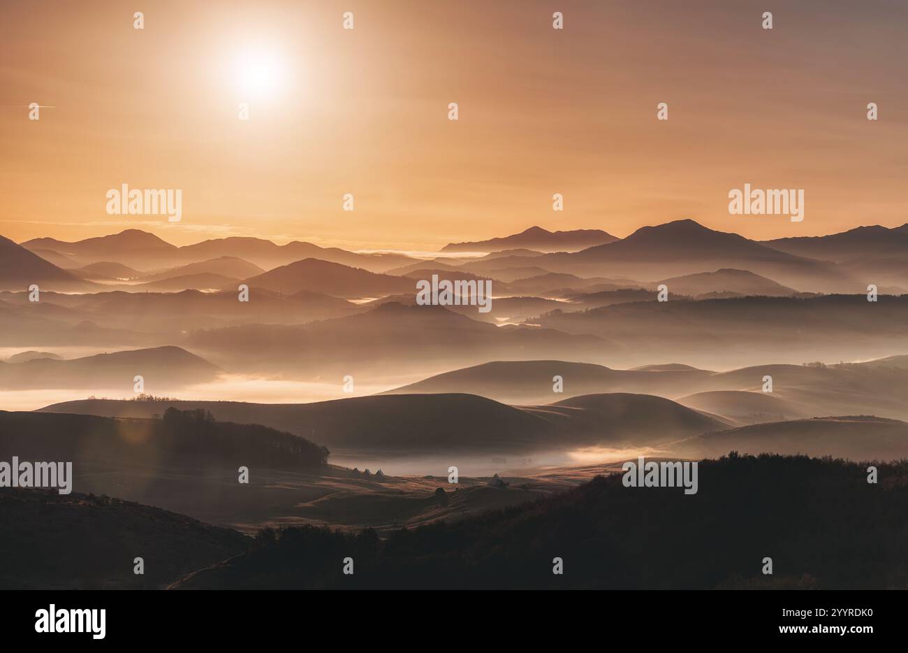 Stunning sunrise casting a warm golden glow over layers of rolling ...