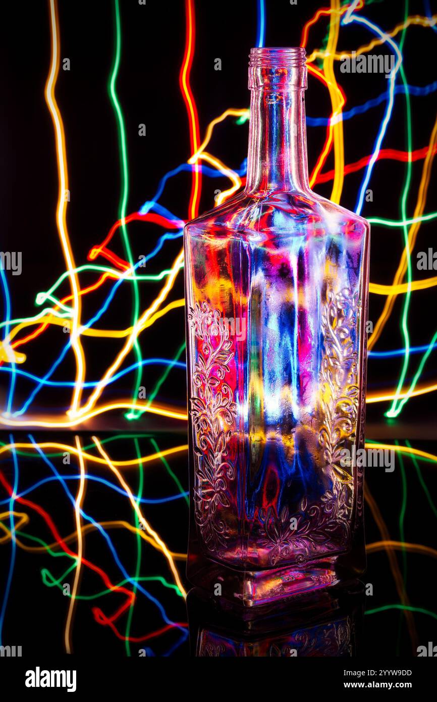 Glass Bottle Surrounded by Multicolored Light Trails on Black Stock Photo