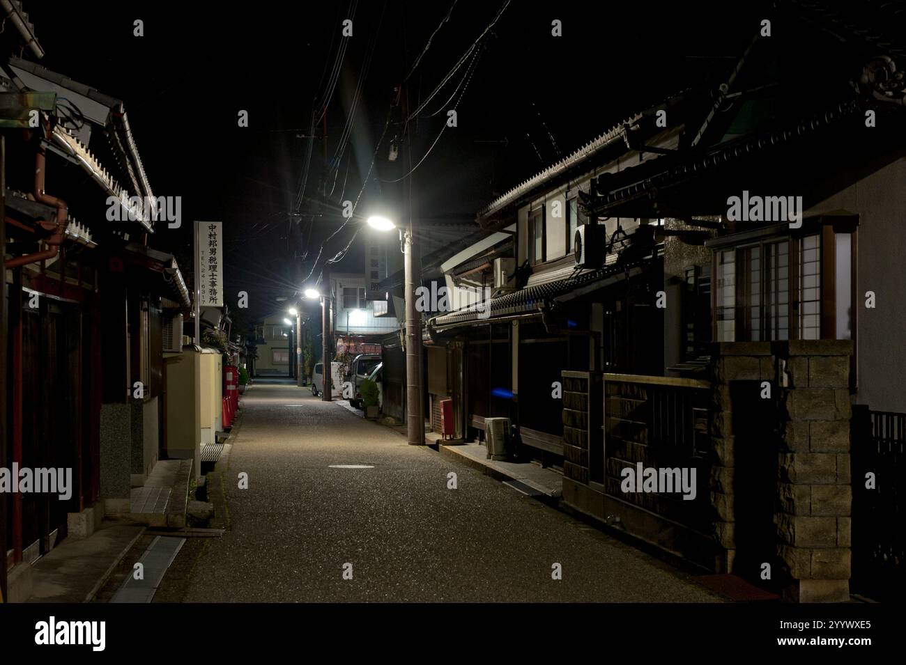 A typical small town Japanese residential street at night with single-family homes lining each side in Japan. Stock Photo