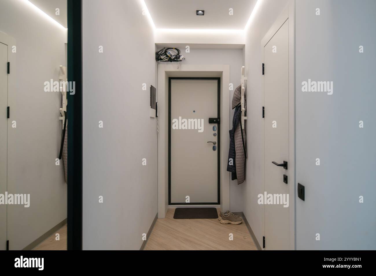 Modern hallway interior. White walls, wood floor, black door, full ...