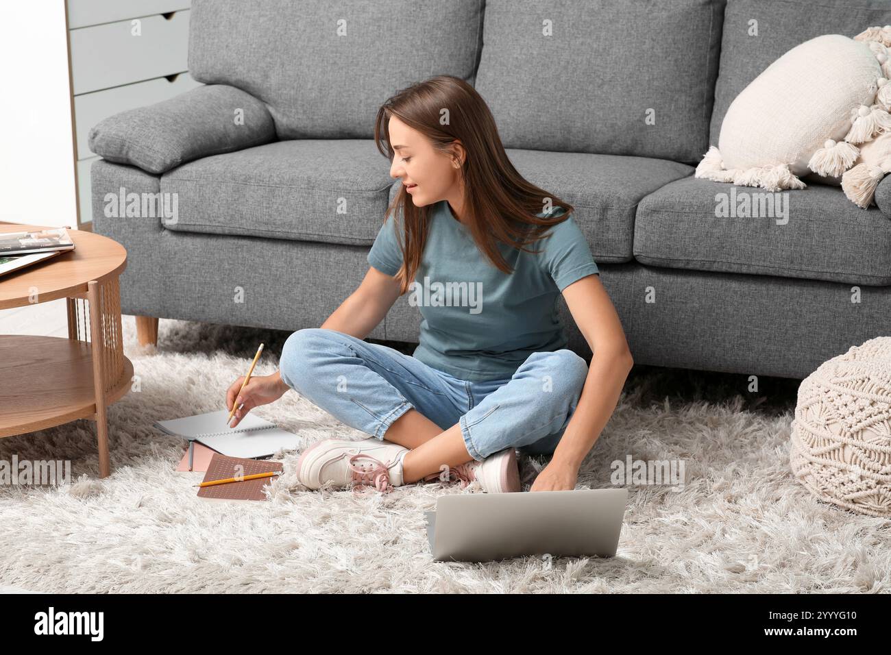 Beautiful woman with laptop writing in notebook at home Stock Photo - Alamy
