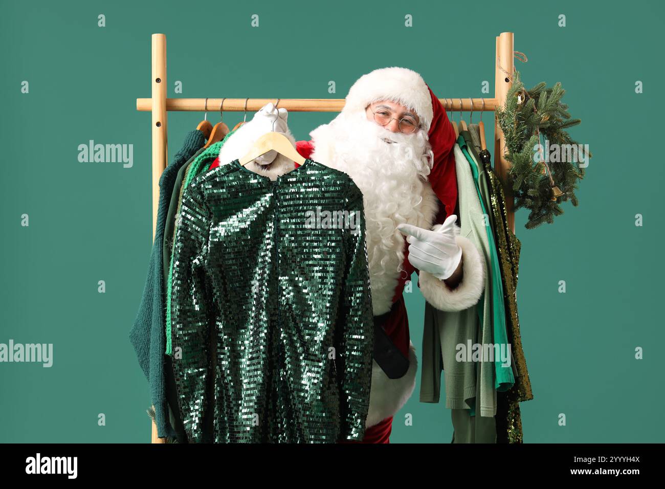 Santa Claus pointing at hanger with stylish dress near rack with ...