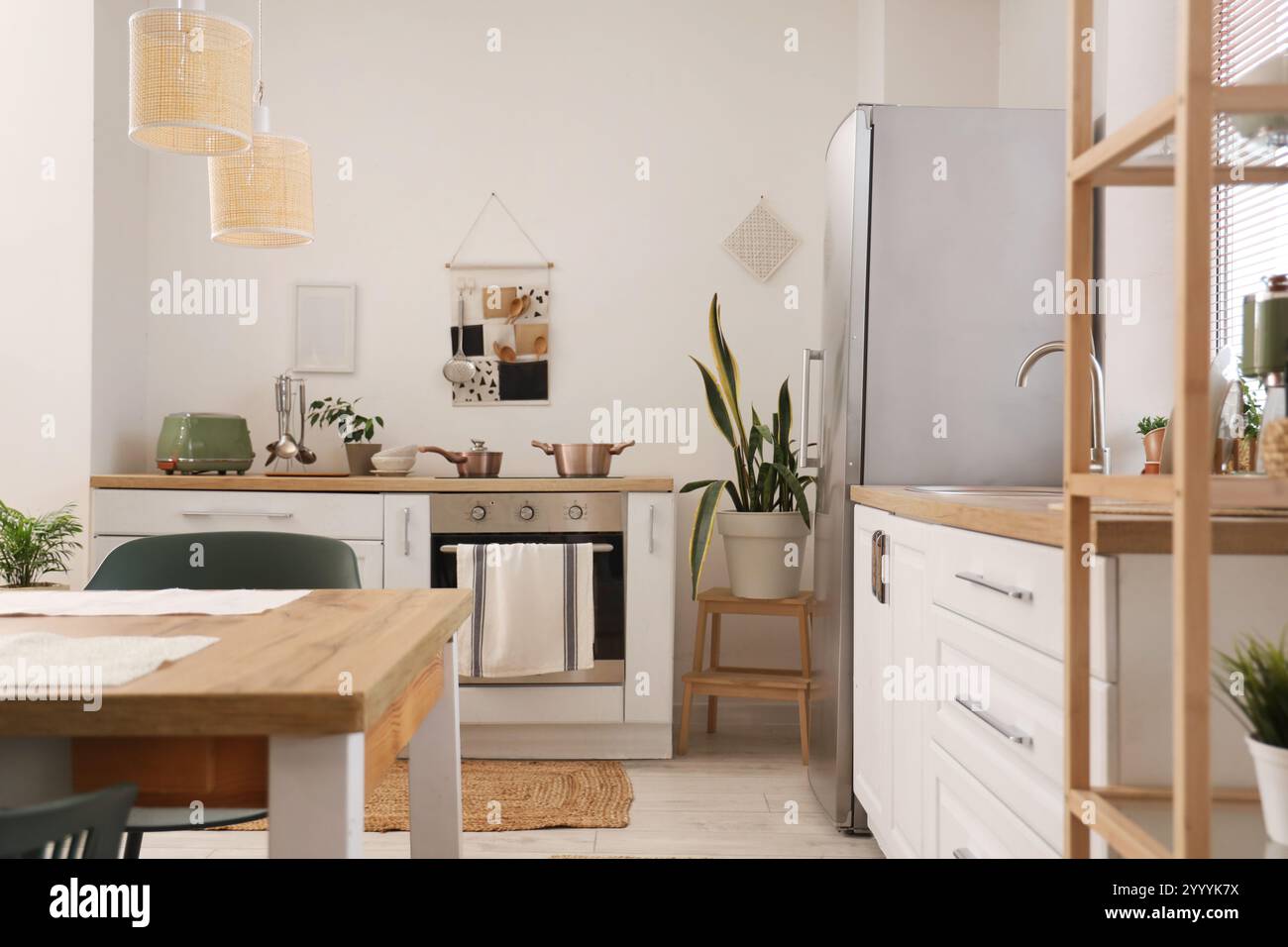 Interior of stylish kitchen with dining table, white counters and ...