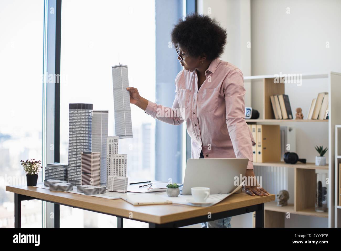 African American female architect in office setting holding building ...