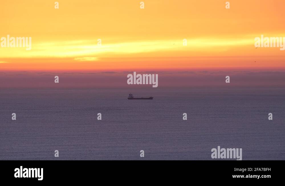 beautiful sunset sky over the sea with cargo ship on the horizon 4k ...