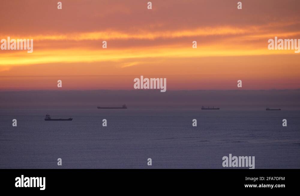 beautiful sunset sky over the sea with cargo ship on the horizon slow ...