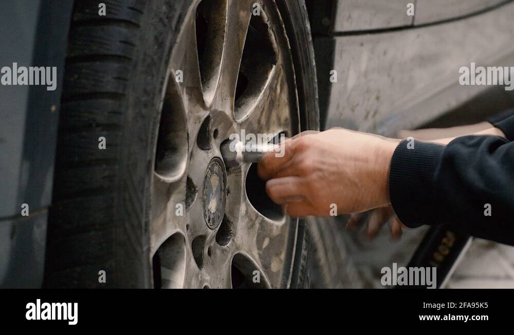 Man putting the tire bolts back into the sockets after he changed the