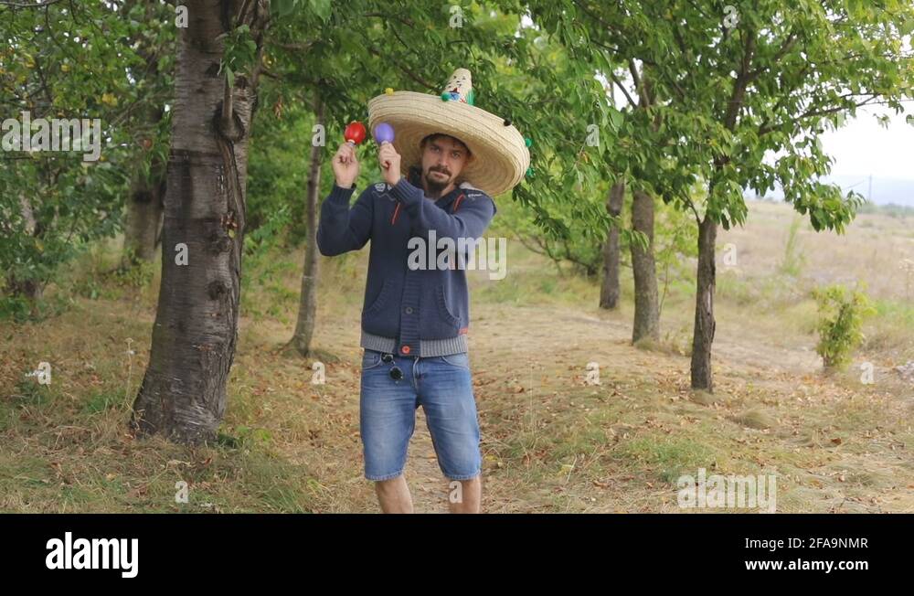 Young Mexican guy in sombrero shaking maracas playing music having fun