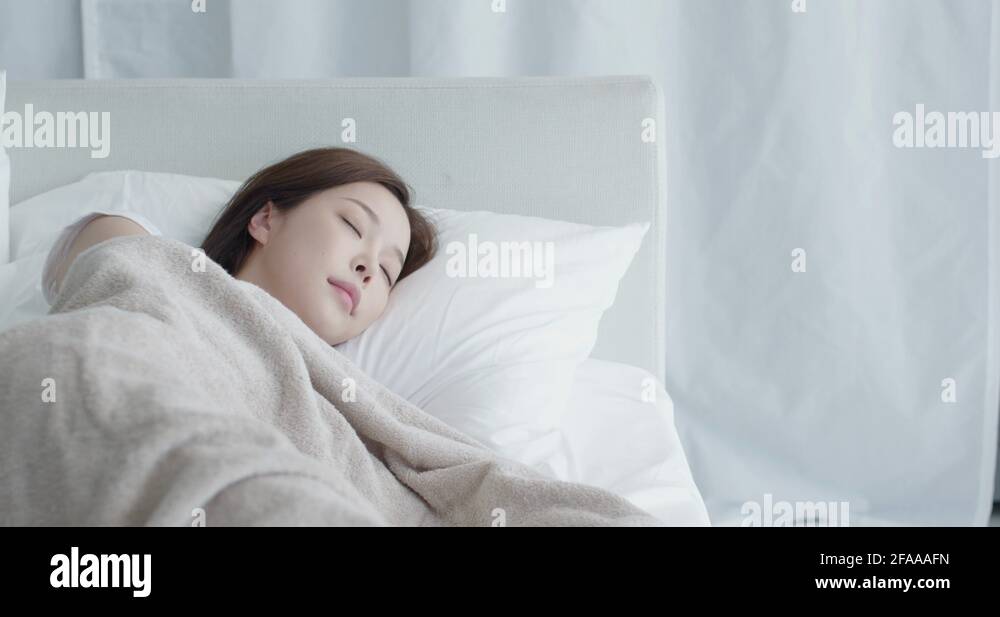 A young Korean woman lying in bed and sleeping comfortably Stock Video ...