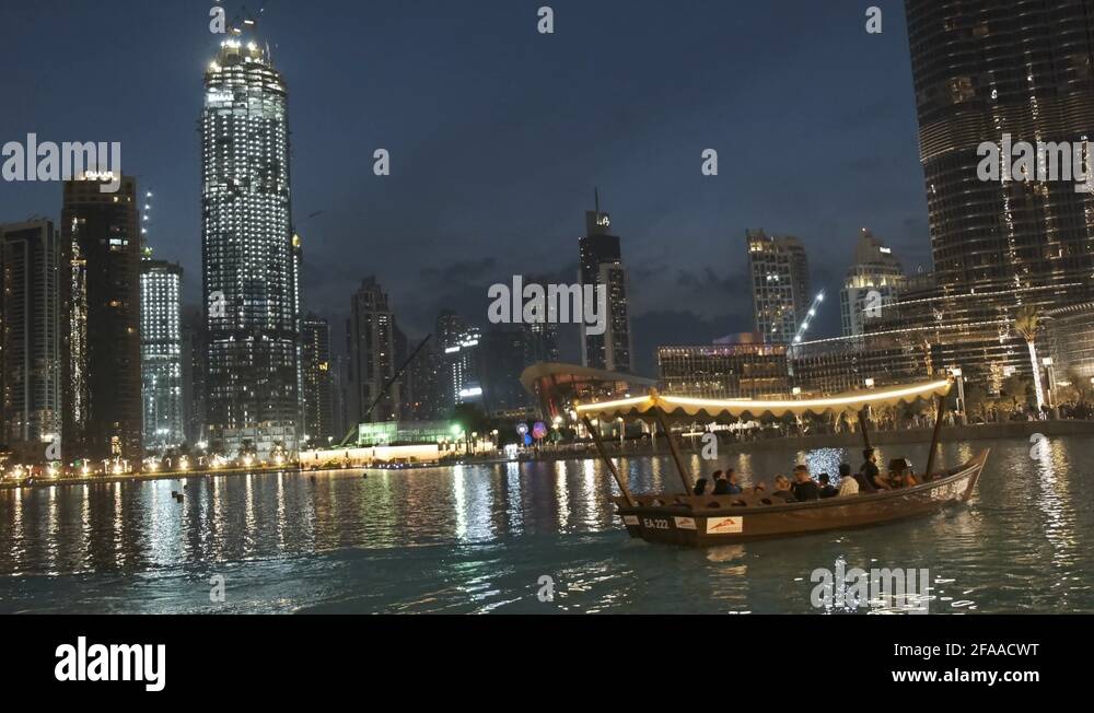 Tourist boat going on a tour in the Dubai fountain alongside highrise