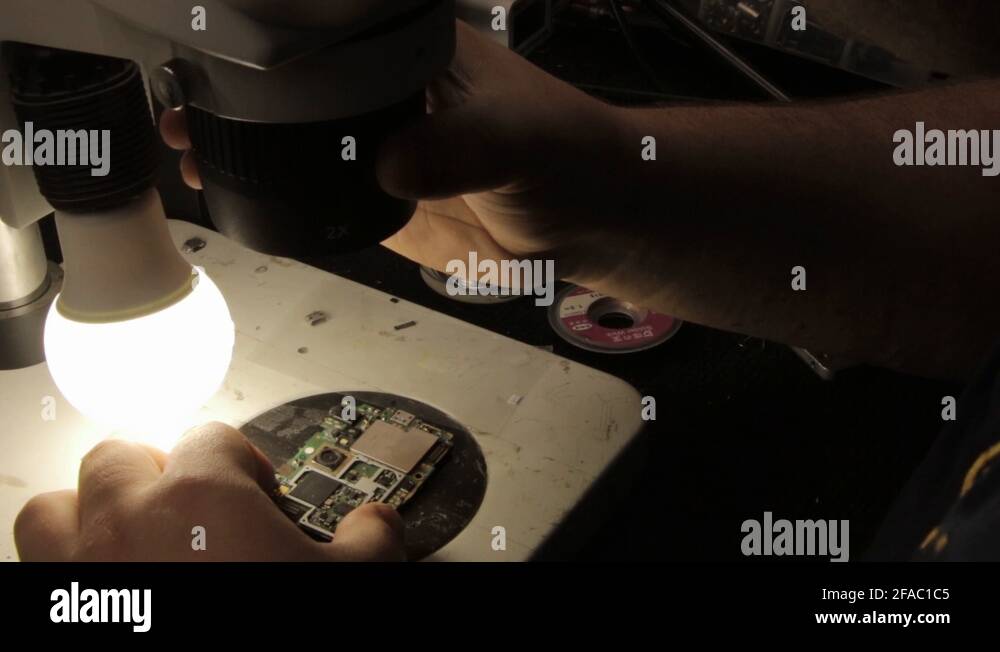 The master examines a printed circuit board under an electron