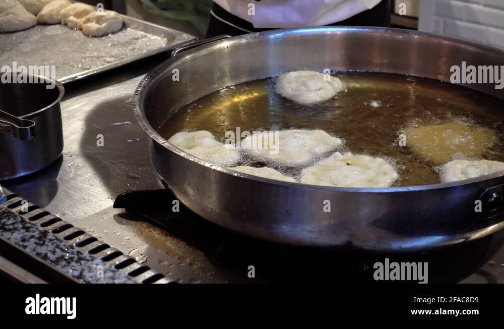 Process of preparing donuts from dough. Chef fry donuts in boiling oil
