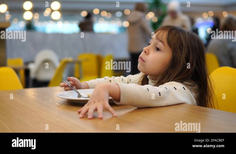 Blonde girl 45 years old eats pancake. Child on the food court. Eating