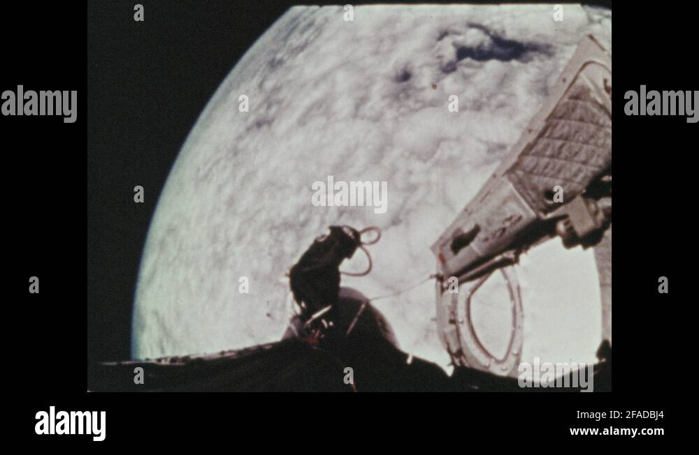 1960s: Astronaut floating in space, on tether, above bay of Space ...