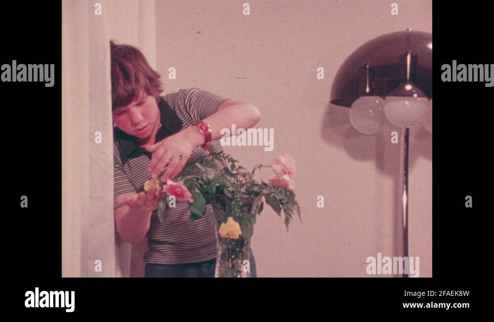 1970s: Boy lifts dead rose from trash and examines it. Woman kneels by ...