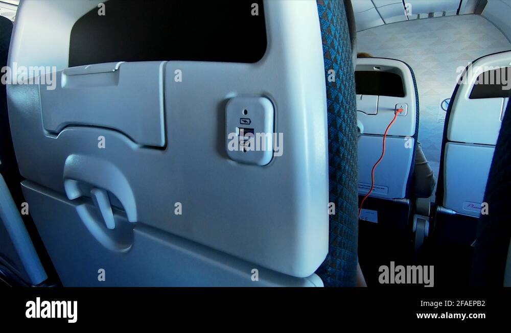 Footage of a traveler plugging into a USB port on an airplane. 4K Stock