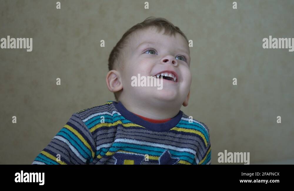 Close up of a two years old boy is watching TV in a dark room Stock