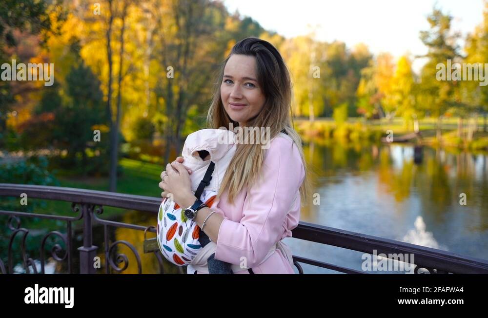 girl smiling with baby in sling, newborn child having good sleep in baby sling Stock Video