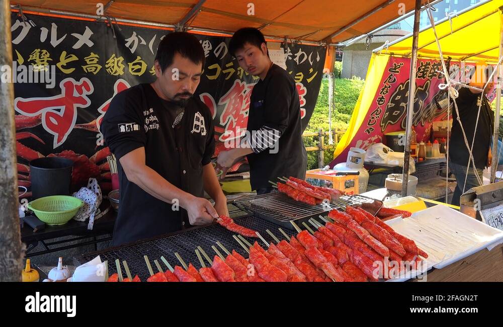 Cooks are grilling crab sticks (surimi) on a street food court. Tokyo