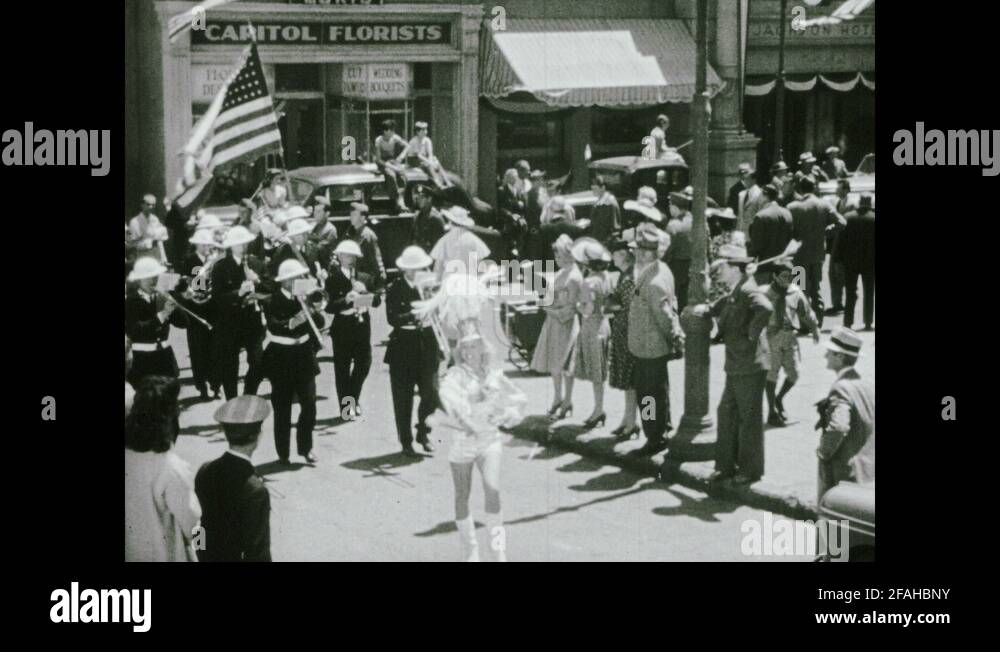 1940s City street, parade, baton twirler, marching band, man carries