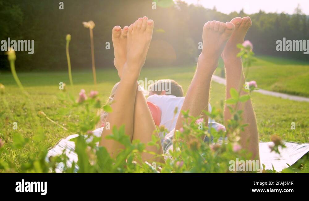 SLOW MOTION Man and woman lying in meadow and playfully kicking their