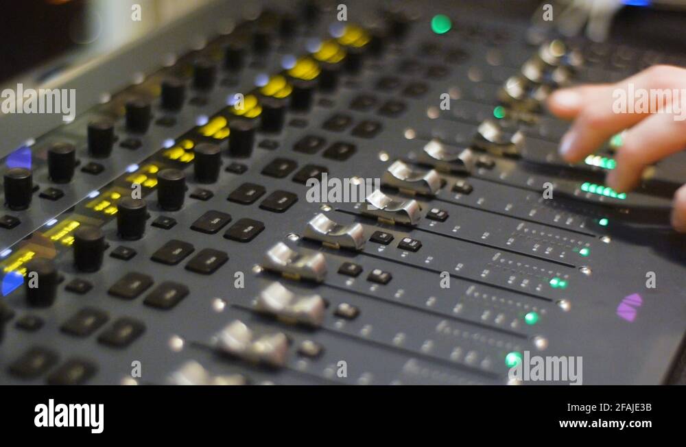 Recording studio digital audio mixer faders and sliders being operated
