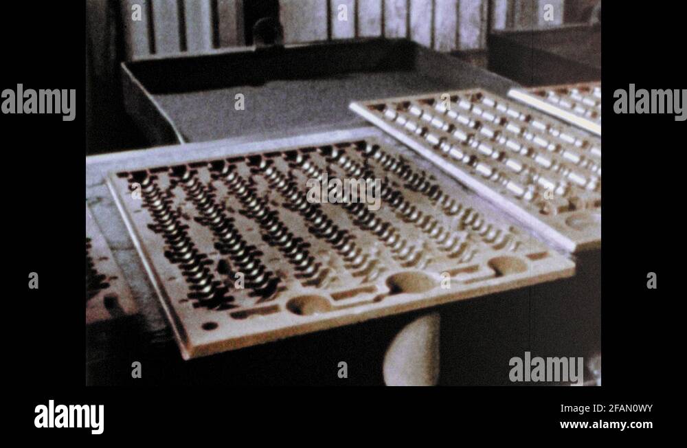 1960s UNITED STATES metal in molds on conveyor. Man puts mold on