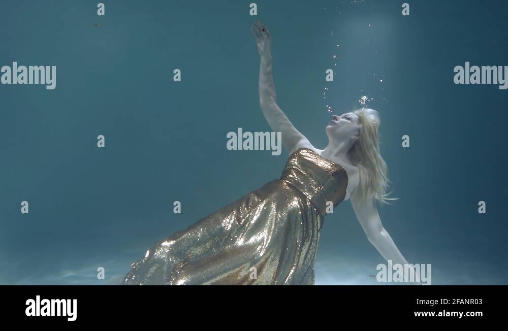 adult sinking woman is floating near ground, looking up, trying to swim