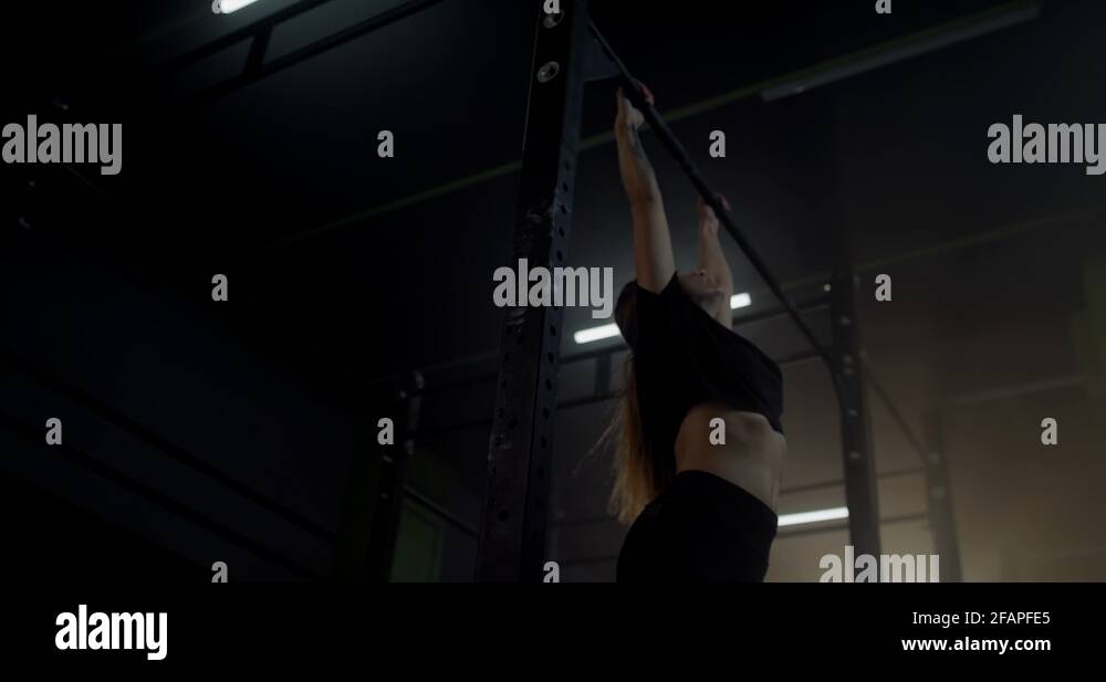Caucasian female athlete practicing pull ups in a gym. Functional ...